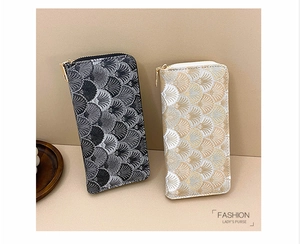 Detailed view of long zip-around purses with elegant shell jacquard texture in two colors