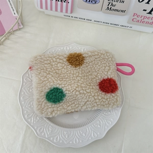 Macro detail of plush polka dot makeup bag on a white ceramic plate background