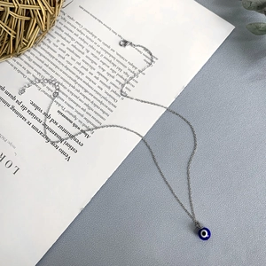 Détail du collier avec pendentif œil maléfique argenté, breloque nazar et fermoir homard