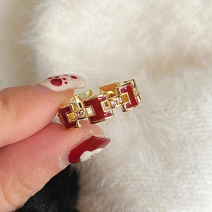 Macro view of gold-plated H-letter ring with red enamel and pavé zircon detailing