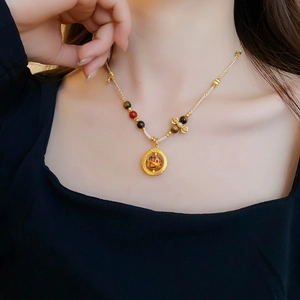Elegant gold-tone beaded necklace with a circular sphere pendant on a model neck