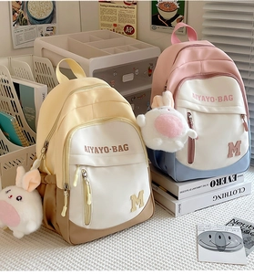Close-up of stylish contrast-color school backpack with a cute rabbit plush pendant