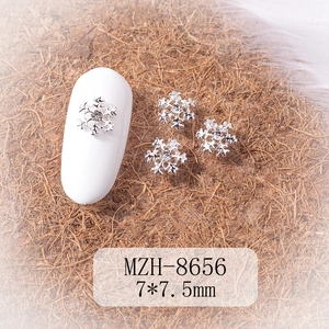 Macro shot of silver snowflake nail art charms with crystal centers on nails