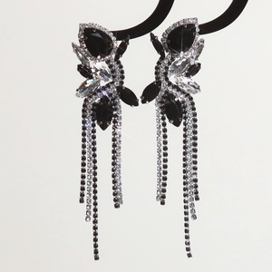 Macro view of long fringe rhinestone earrings with black marquise gems and silver tassels