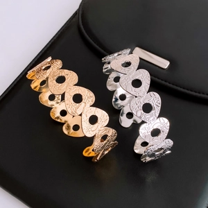 Detail view of gold and silver open bracelets with hollow heart patterns and floral relief