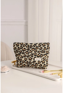 Detail of leopard jacquard makeup bag on a tray with makeup brushes and floral decor