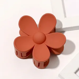 Macro detail of a matte brick red flower hair claw clip with a secure grip structure