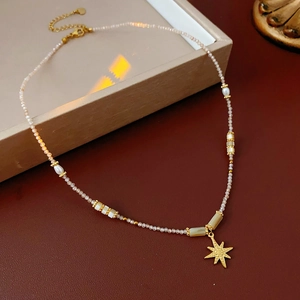 Detail of gold star pendant necklace with freshwater pearls on a display box