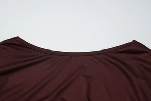 Dettaglio dello scollo a V e della trama in maglia fine su un abito bordeaux aderente