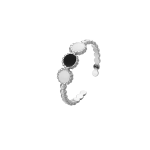 Detailed macro of silver bead band ring featuring black and white enamel circular settings