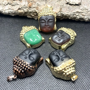 Five assorted Buddha head pendants with colorful resin faces and golden metal edging