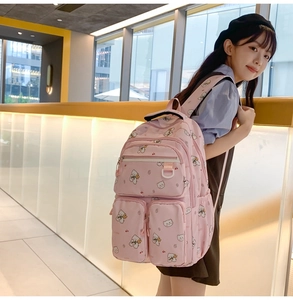 Pink student backpack with bear and cherry prints, shown being worn by a model in detail