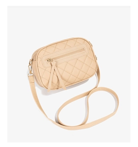 Detail view of beige quilted crossbody bag with triple zippers and adjustable shoulder strap