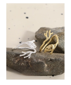Detailed view of S925 sterling silver branch and leaf rings on a natural rock surface
