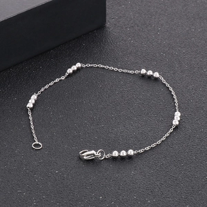 Detailed view of silver beaded stainless steel chain necklace on a black textured surface