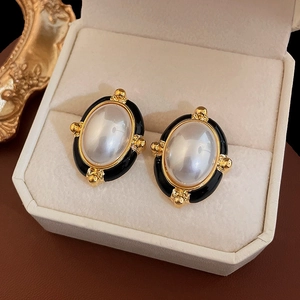 Détail de boucles d'oreilles vintage ovales plaquées or avec émail noir et perle