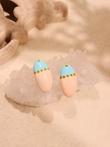 Close-up of oval enamel earrings with blue and pink color-block and yellow dot detail