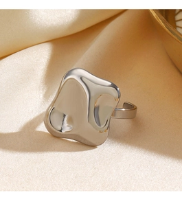 Macro view of silver organic-shaped hammered titanium ring on beige satin fabric
