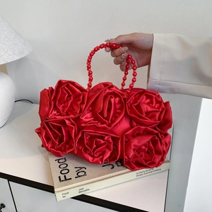 Elegant red silk satin rose clutch bag with beaded handle on a vintage book backdrop