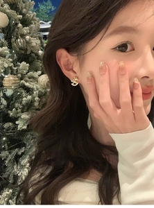 Close-up of golden rocking horse earring with zircon crystals on a model ear