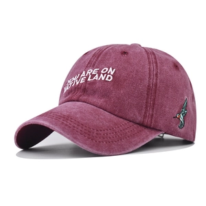 Detail of burgundy washed cotton baseball cap with white embroidery and hummingbird side patch