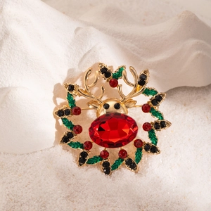 Detail of Christmas reindeer brooch with red gemstone nose and green enamel leaf wreath