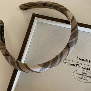 Detailed view of khaki plaid bow headband placed on a vintage wooden jewelry box