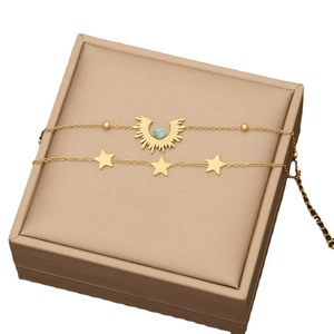Double-layered gold necklace featuring a turquoise wing pendant and small star charms