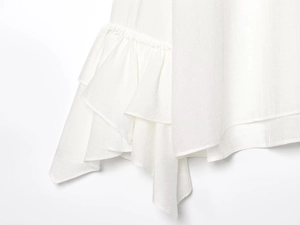 Close-up van witte geweven blouse met elegante gelaagde ruches en verfijnde stoftextuur