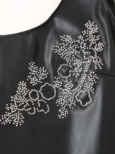 Close-up of intricate silver bead embroidery on black faux leather dress fabric