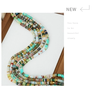 Macro shot of colorful natural stone abacus beads and gold spacer beads in a white tray
