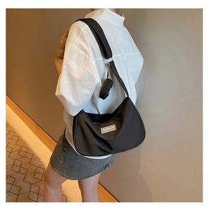 Detailed view of a black nylon crescent crossbody bag with a small round coin purse