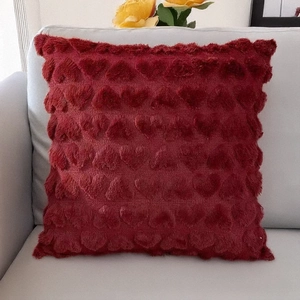 Close-up of deep red plush heart pattern pillow cover on a gray sofa