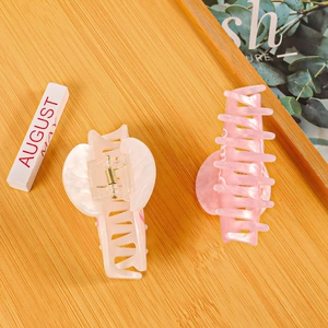 Pink and white Bride letter PVC hair claws on a bamboo tray with lifestyle props