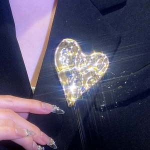 Broche cœur dorée texturée avec cristaux étincelants sur le revers d'un blazer noir