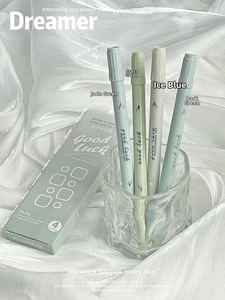 Detail view of dual-tip Morandi highlighters in a glass cup on white silk fabric