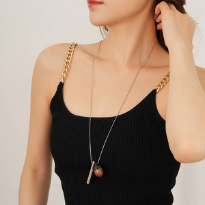 Detail of wooden acorn pendant with silver chain necklace on model for styling
