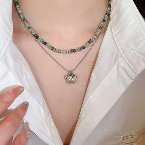 Close-up of a double-layer stainless steel necklace with colorful beads and a floral pendant