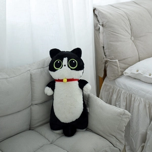 Détail d'une peluche de chat avec de grands yeux verts et un collier rouge à clochette