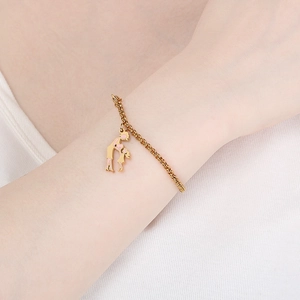 Gros plan du bracelet en or avec pendentif mère et fille en émail rose sur le poignet