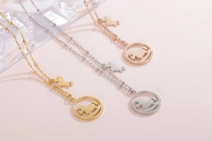 Détail de pendentifs cheval à bascule en or, argent et or rose sur fond rose poudré
