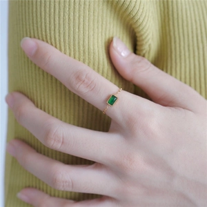 Macro detail of 18K gold chain ring featuring an emerald-cut green zircon stone