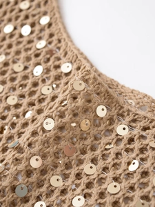 Détail macro du tissu tricoté kaki avec paillettes dorées et texture crochet