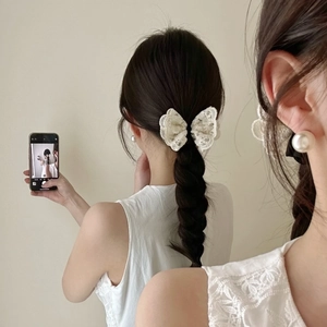 Détail d'un bandeau en dentelle blanche et boucles d'oreilles perles sur coiffure tressée
