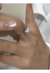 Primo piano di un elegante anello in argento con una grande perla grigia sul dito di una modella