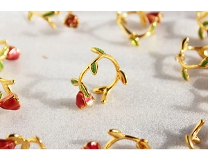 Macro detail of French rose ring with red enamel flower bud and green leaf accents