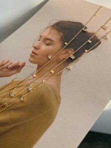 Detailed view of gold titanium necklaces with geometric zircon charms on art magazine
