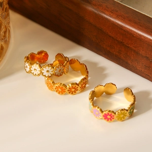Macro shot of colorful enamel daisy flowers on a gold-plated adjustable stainless steel ring