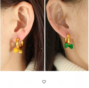 Detail view of gold hoop earrings with yellow and green gemstone bow charms