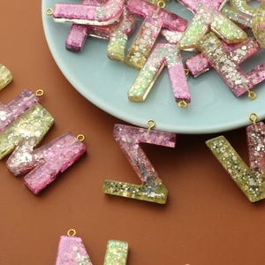 Resin glitter letter charm, DIY keychain pendant, crystal epoxy alphabet jewelry detail.